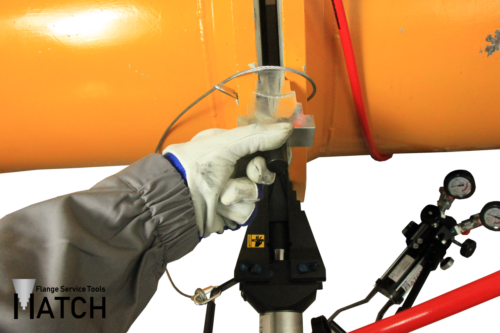 Hydraulic flange spreader (HSW15TEX) in between orange pipes with hydraulic hand pump (P350BEX) and safety block
