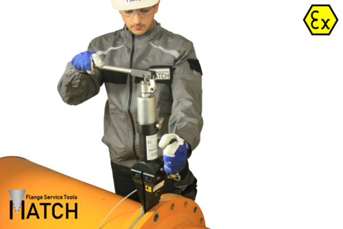 Employee operating the integral flange spreader (HSW15TSCEX) on an orange pipe.